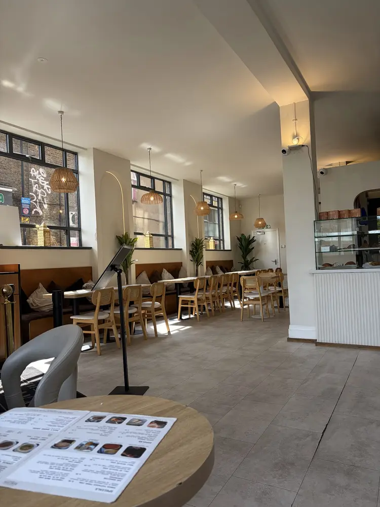 The cafe's light-filled seating area with cane chairs, wooden benches and rattan pendant lights